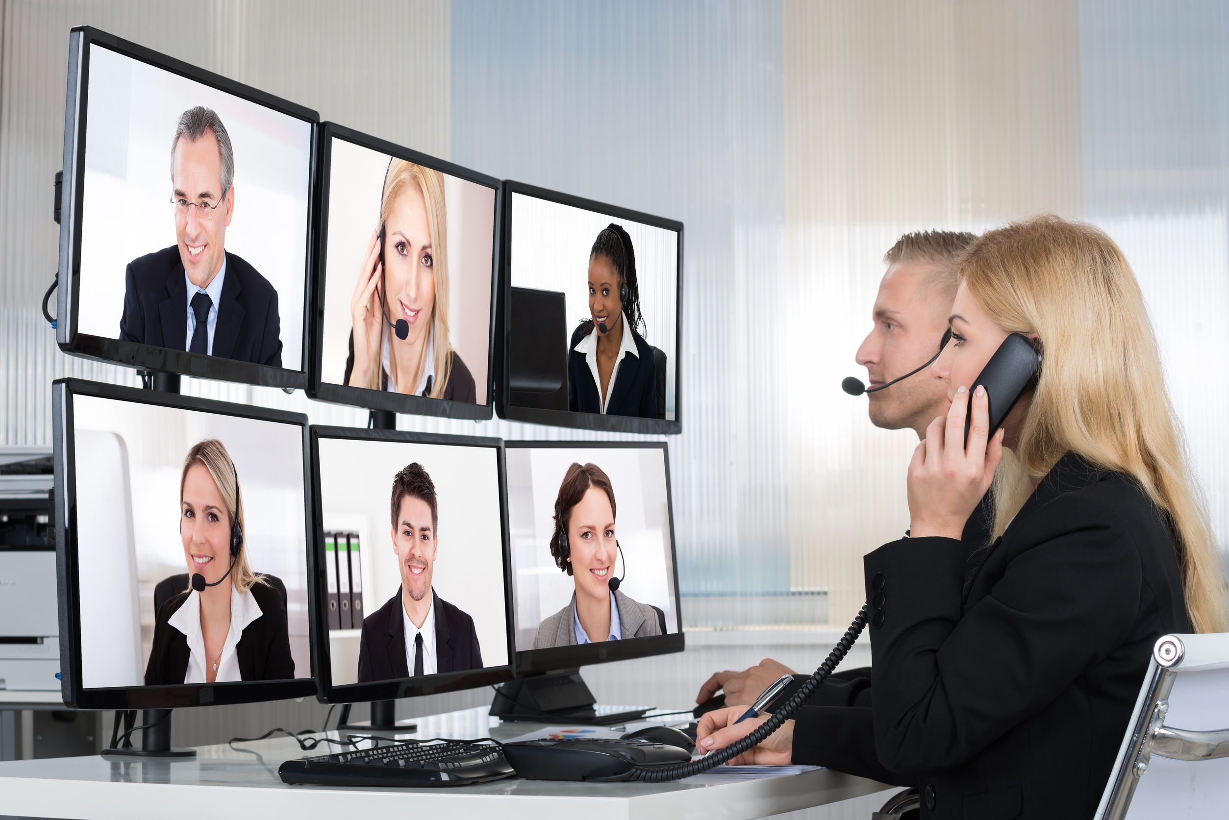 50245633 - business people having conference call with multiple computer screens at table in office